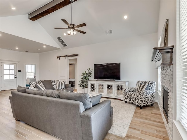 1718 Zayden Ln, Norman, OK 73072 - living room featuring light wood-type flooring, a fireplace, ceiling fan, a barn door, and beamed ceiling