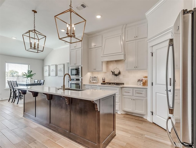1718 Zayden Ln, Norman, OK 73072 - kitchen with light wood-type flooring, stainless steel appliances, a kitchen island with sink, pendant lighting, and white cabinetry