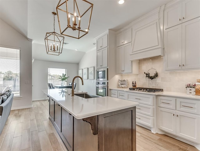 1718 Zayden Ln, Norman, OK 73072 - kitchen with stainless steel appliances, a center island with sink, light hardwood / wood-style flooring, white cabinets, and lofted ceiling