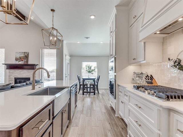 1718 Zayden Ln, Norman, OK 73072 - kitchen featuring a fireplace, white cabinets, a center island with sink, and light hardwood / wood-style flooring