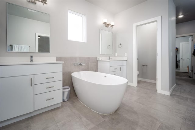 bathroom with tile patterned flooring, toilet, a bathtub, vanity, and tile walls