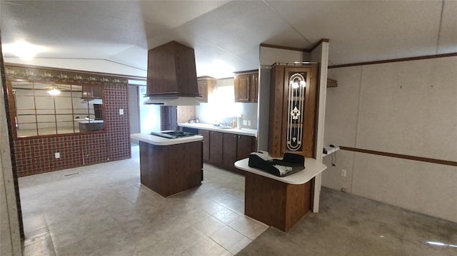 kitchen with a center island, lofted ceiling, sink, custom range hood, and stainless steel gas cooktop