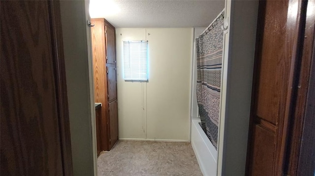 bathroom with a textured ceiling and shower / tub combo