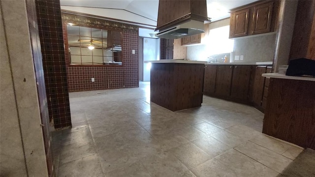 kitchen with vaulted ceiling, ceiling fan, tile walls, a kitchen island, and custom range hood