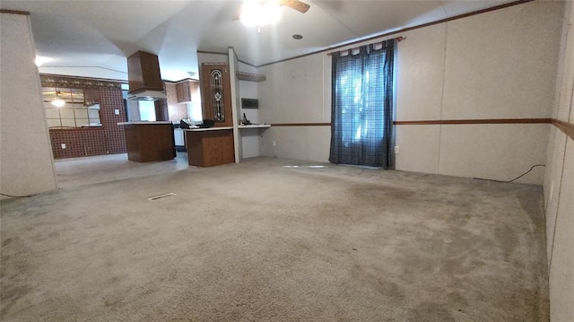 interior space with ceiling fan, custom range hood, light colored carpet, and vaulted ceiling