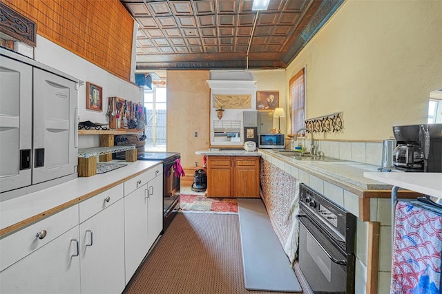 kitchen featuring pendant lighting, white cabinets, black appliances, sink, and kitchen peninsula