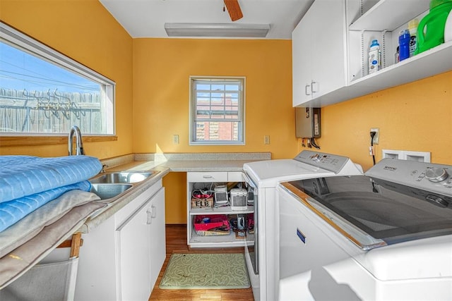 clothes washing area featuring cabinets, wood-type flooring, sink, and washing machine and clothes dryer