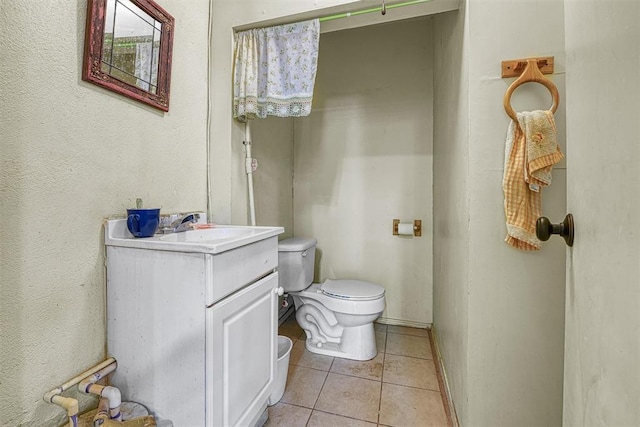 bathroom with toilet, vanity, and tile patterned floors