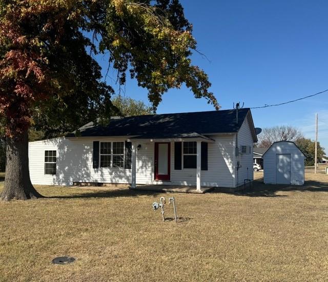 ranch-style house featuring a front lawn and a storage unit