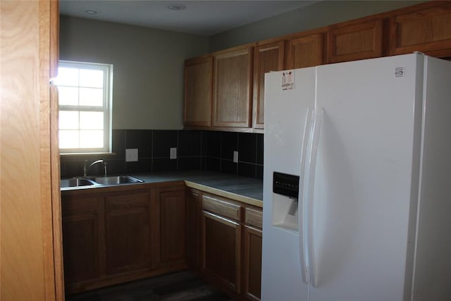 kitchen featuring white fridge with ice dispenser, sink, dark wood-type flooring, and tasteful backsplash