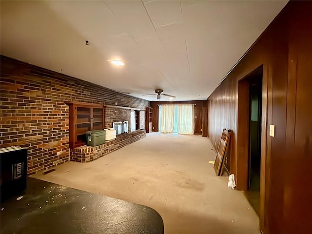 basement featuring a wood stove, ceiling fan, and brick wall