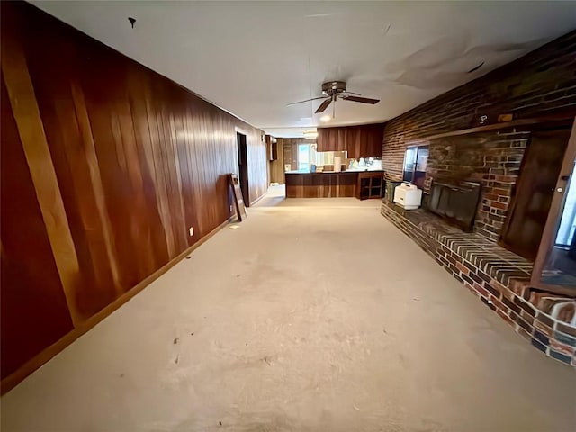 unfurnished living room featuring ceiling fan, brick wall, and wooden walls