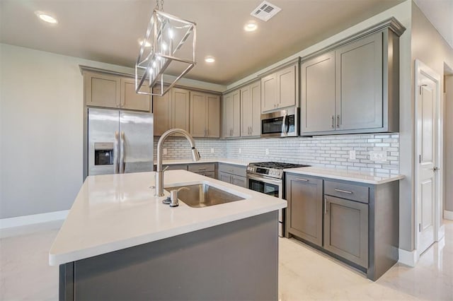 kitchen featuring gray cabinets, sink, a center island with sink, and appliances with stainless steel finishes