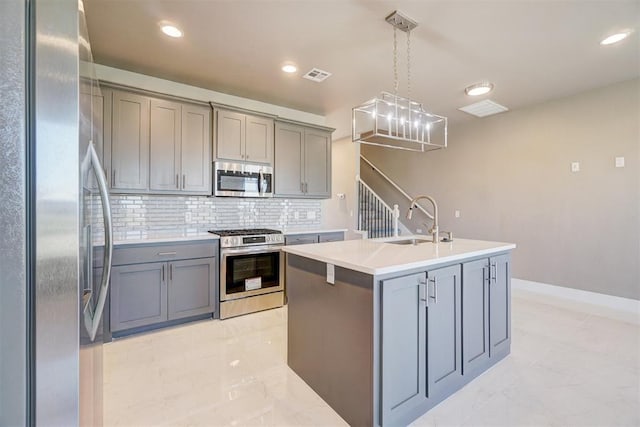 kitchen with appliances with stainless steel finishes, sink, pendant lighting, a center island with sink, and gray cabinets