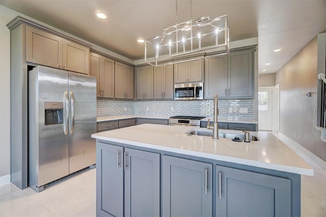 kitchen with appliances with stainless steel finishes, a kitchen island with sink, sink, pendant lighting, and gray cabinets