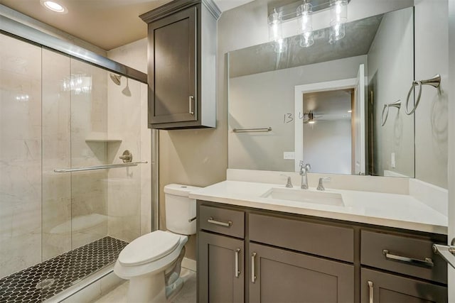 bathroom featuring ceiling fan, a shower with door, vanity, and toilet