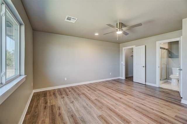 unfurnished bedroom featuring a closet, light hardwood / wood-style flooring, ensuite bath, and ceiling fan