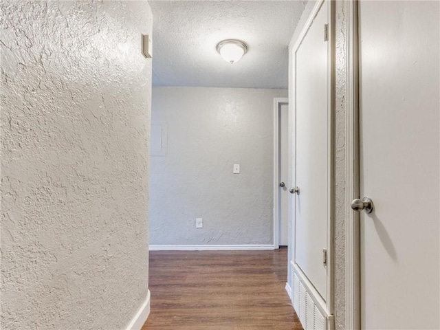 hallway with dark hardwood / wood-style floors and a textured ceiling