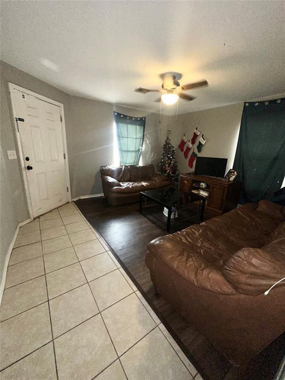 living room with light tile patterned floors, a textured ceiling, and ceiling fan