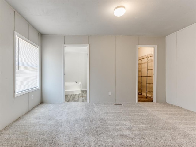 unfurnished bedroom featuring ensuite bath and light carpet