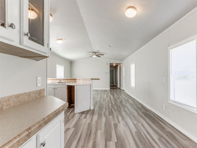 kitchen with ceiling fan, lofted ceiling, white cabinetry, and light hardwood / wood-style flooring