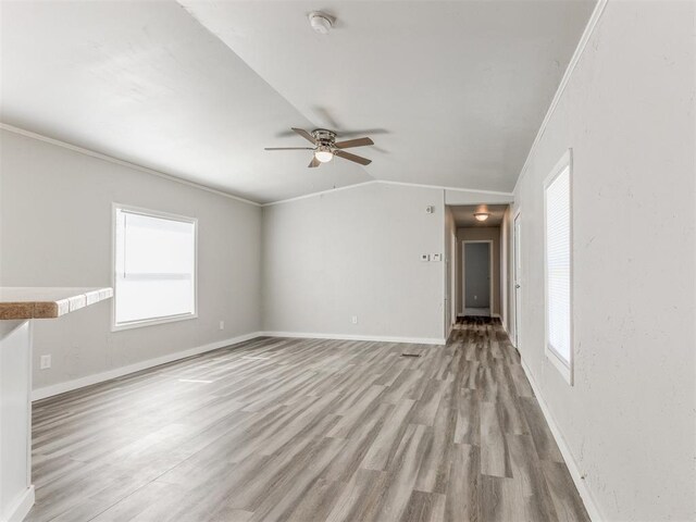 unfurnished living room featuring ceiling fan, crown molding, light hardwood / wood-style floors, and lofted ceiling