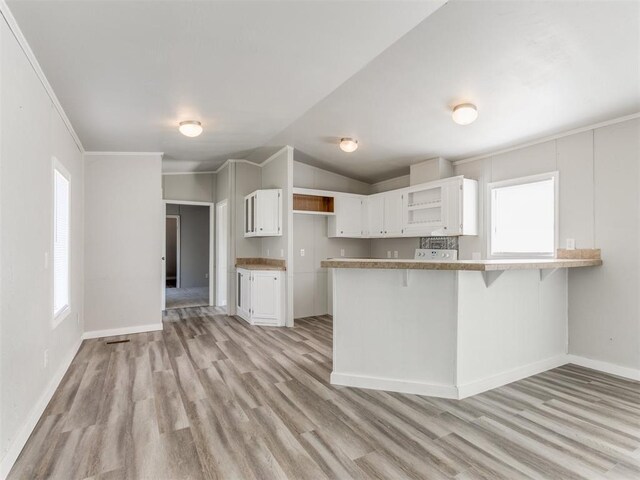 kitchen with white cabinets, plenty of natural light, light hardwood / wood-style floors, and kitchen peninsula