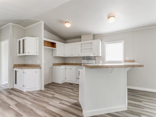 kitchen with vaulted ceiling, white electric range, light hardwood / wood-style floors, white cabinetry, and a breakfast bar area