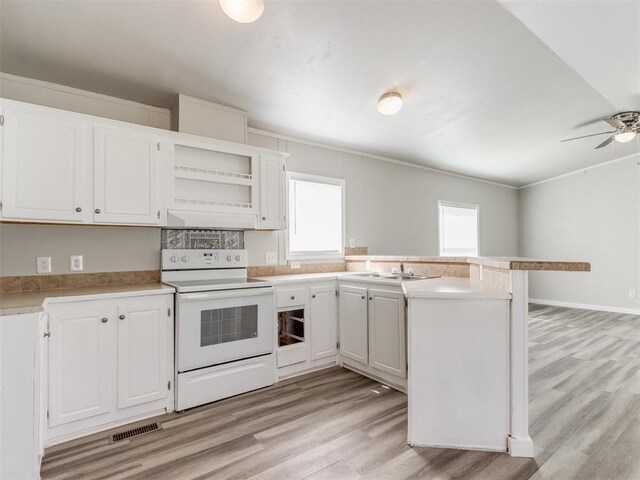 kitchen with white range with electric stovetop, kitchen peninsula, white cabinetry, and light hardwood / wood-style flooring