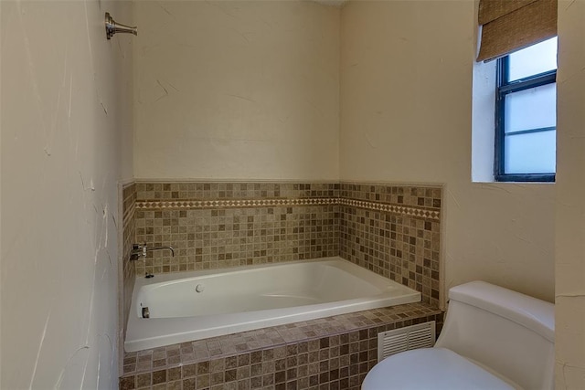 bathroom featuring tiled bath and toilet