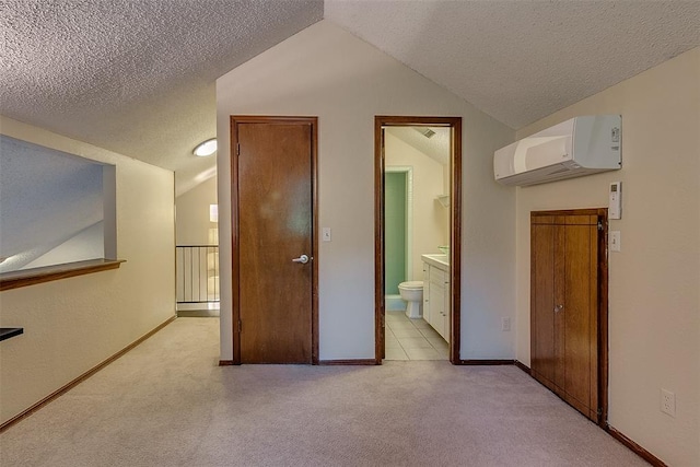 interior space with an AC wall unit, a textured ceiling, light colored carpet, and vaulted ceiling