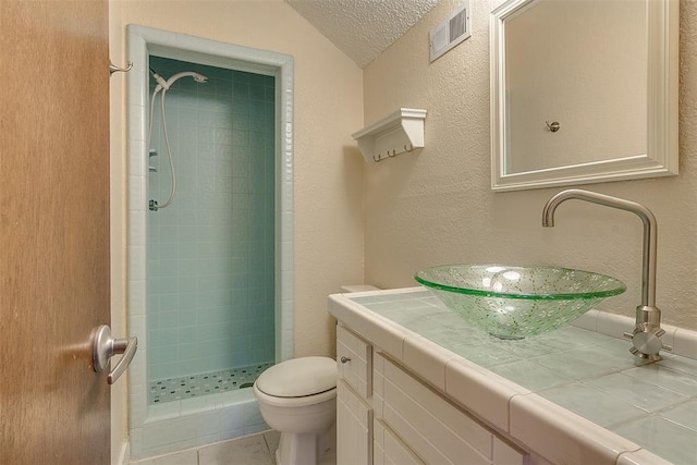 bathroom with vanity, a shower, tile patterned flooring, toilet, and a textured ceiling