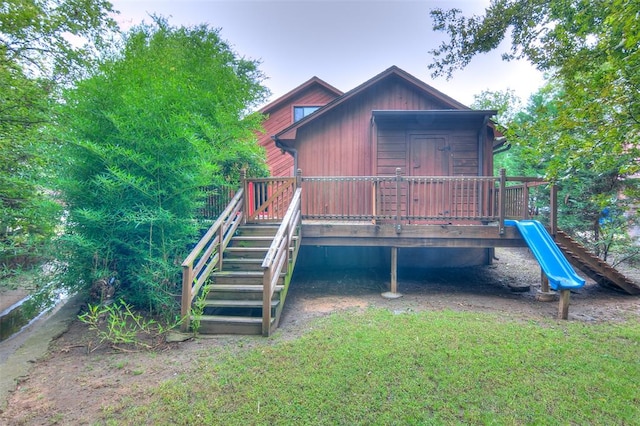 rear view of property with a playground and a deck