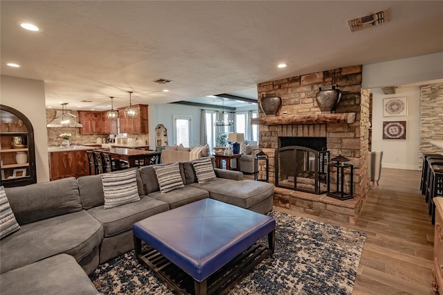 living room with light wood-type flooring and a stone fireplace