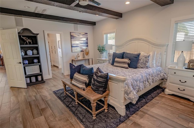 bedroom featuring beamed ceiling, ceiling fan, light wood-type flooring, and multiple windows