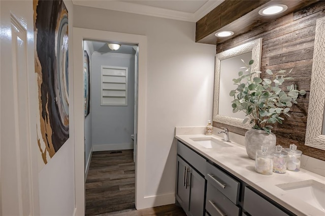 bathroom with toilet, vanity, wood-type flooring, and ornamental molding