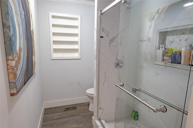 bathroom with hardwood / wood-style floors, toilet, and a shower with shower door