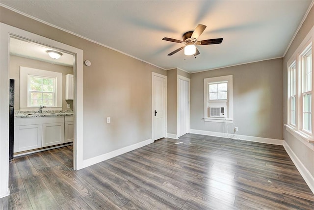 spare room with dark wood-type flooring, cooling unit, sink, crown molding, and ceiling fan