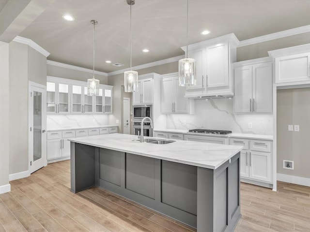 kitchen with an island with sink, stainless steel appliances, white cabinetry, and sink