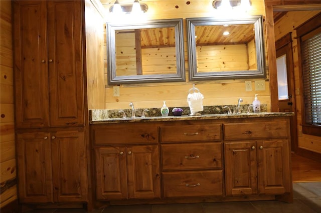 bathroom with tile patterned flooring, vanity, and wooden walls