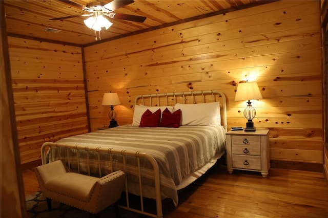 bedroom with wooden walls, ceiling fan, light wood-type flooring, and wood ceiling