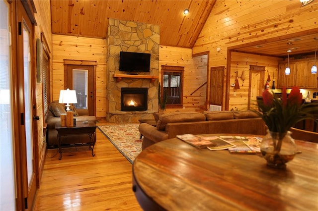 interior space with light hardwood / wood-style floors, wood ceiling, a fireplace, and wooden walls