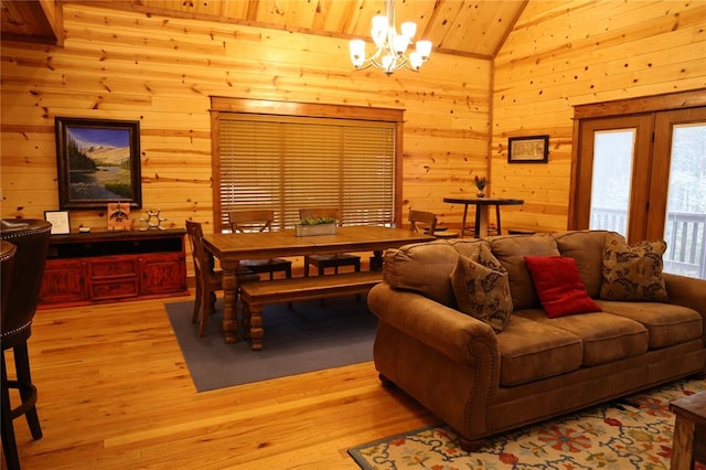 living room featuring an inviting chandelier, high vaulted ceiling, wooden walls, wood ceiling, and light wood-type flooring