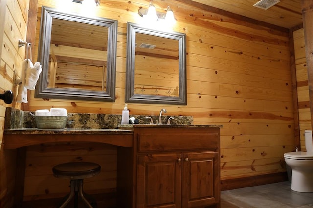 bathroom featuring vanity, toilet, and wood walls