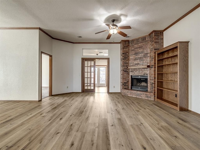 unfurnished living room featuring a fireplace, light hardwood / wood-style floors, a textured ceiling, and ornamental molding