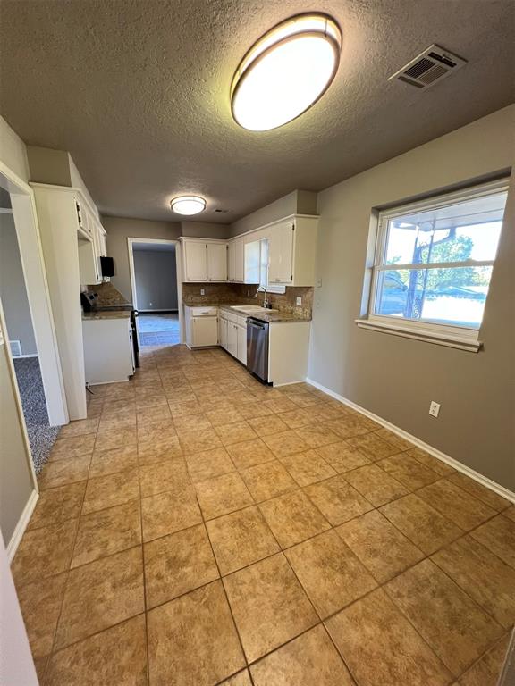 kitchen featuring backsplash, stainless steel dishwasher, a textured ceiling, sink, and white cabinetry