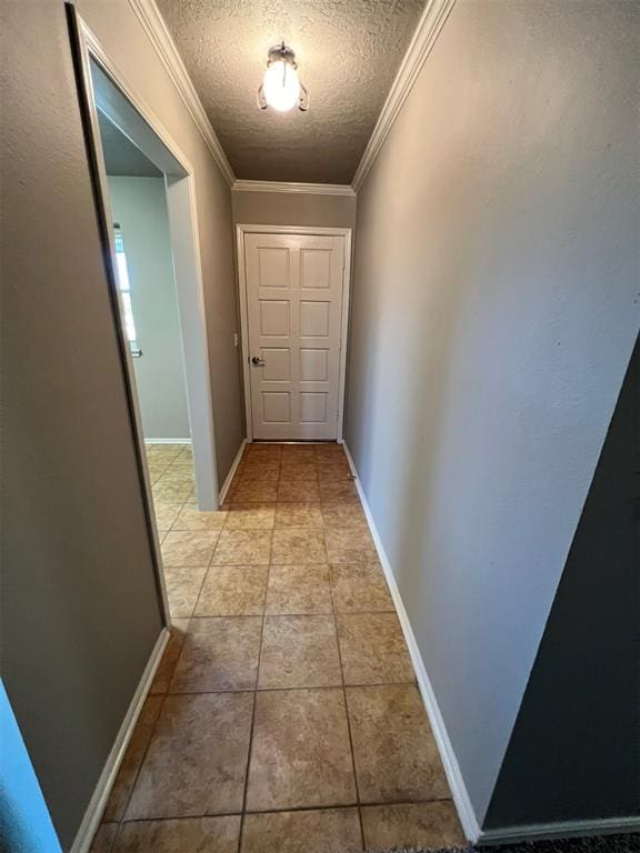 corridor with crown molding, light tile patterned floors, and a textured ceiling