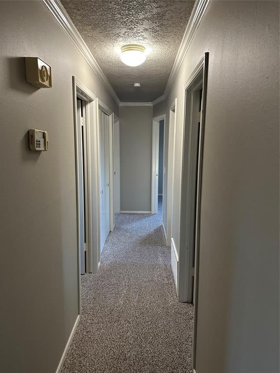 hallway featuring a textured ceiling, light colored carpet, and ornamental molding