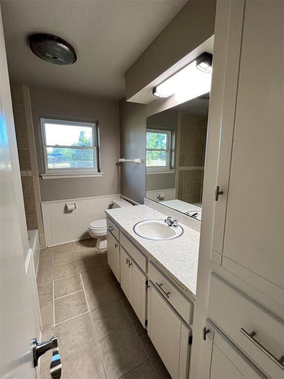 bathroom with tile patterned flooring, vanity, toilet, and plenty of natural light