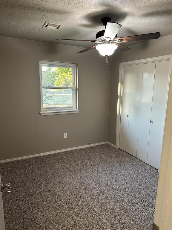 unfurnished bedroom with carpet, ceiling fan, a textured ceiling, and a closet